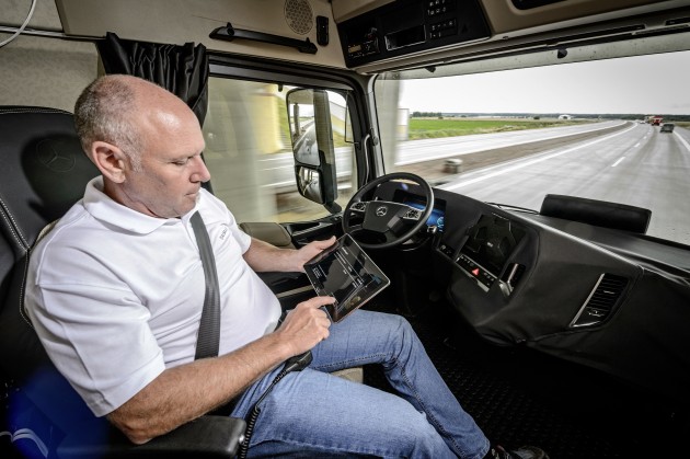 A driver performs other duties while Daimler's autonomous truck guides him down the road.