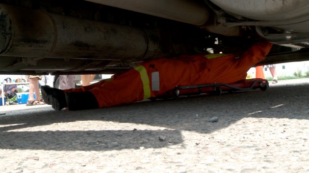 An MTO enforcement officer slides underneath a tractor-trailer during an inspection.